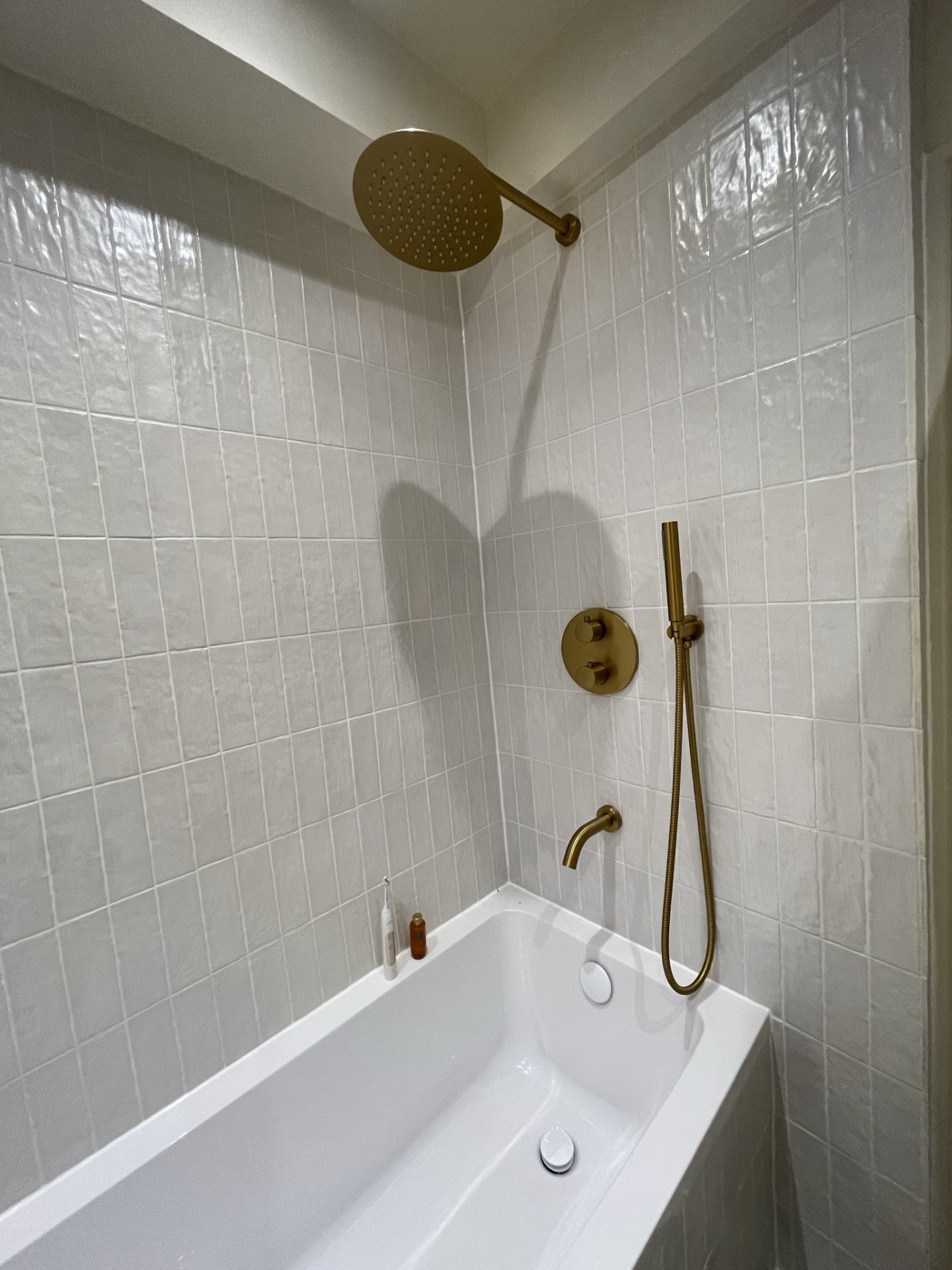 Renovated Shepherd's Bush W12 bathroom with white metro tiling and brushed brass shower fittings
