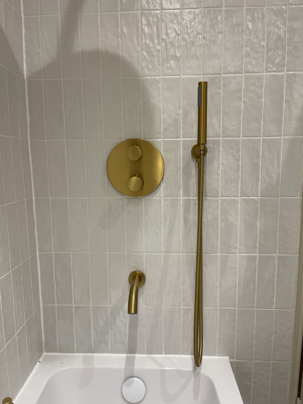 Concealed brushed brass shower valve and handset on white zellige tiling, Shepherd's Bush W12
