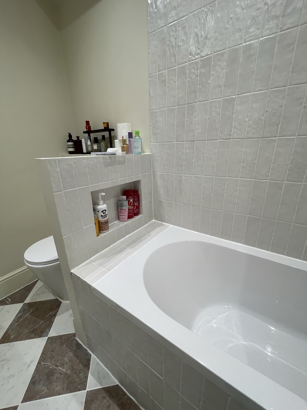 Bath with tiled recessed storage niche and marble chequerboard floor, Shepherd's Bush W12